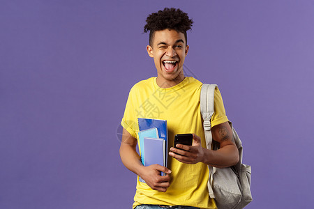回到学校 大学的概念 快乐 微笑的快乐男人 使用手机的学生 乐观地对着镜头眨眼 拿着背包和笔记本 讲座笔记和智能手机爆炸培训班成背景图片