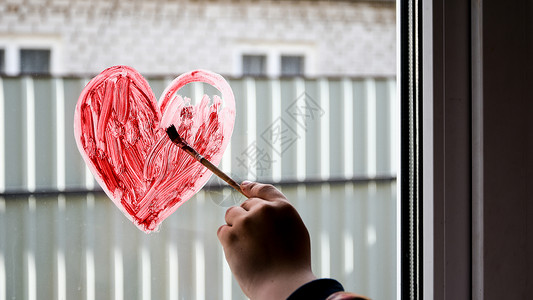 一个女孩的手 在窗户上画着粉刷红心 复制文字空间 呆在家里孩子们刷子绘画玻璃彩虹艺术儿童育儿爱心乐趣背景
