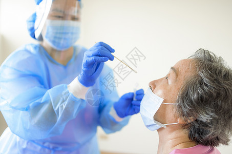 护士从可能感染的高级妇女身上提取可冠状病毒样本的乳液背景图片