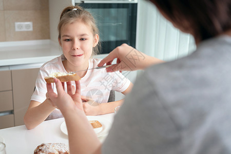 母亲做她女儿的三明治当早餐吃女孩微笑妈妈面包单亲小吃童年桌子女士快乐午餐高清图片素材