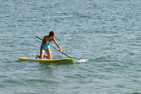 划船的女孩一个十几岁的女孩在SUP董事会上划桨背景