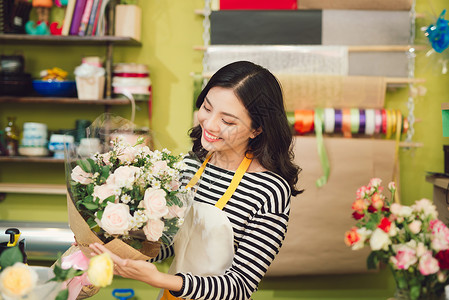 美丽的亚裔女性花女 拿着一束花朵成人园丁围裙零售微笑店铺女士快乐花店职业背景图片