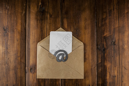 邮件推广工艺信封上有白色空白纸的电子邮件标志位于一张老式木桌上 概念电子邮件消息信件 带复制空间的顶视图品牌邮政垃圾邮件邮件文档办公室桌背景