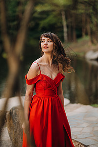 一个年轻漂亮的女孩 长棕色头发 穿着红裙子 环环绕湖边节日高清图片素材