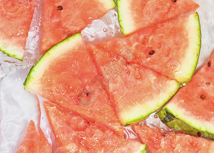 西瓜气泡瓜片在白色背景的水中 带有气泡的液体中的甜瓜特写 红熟瓜片在水中 水果在水中的宏观形象种子食物西瓜饮食晴天飞溅野餐生产果皮收成背景