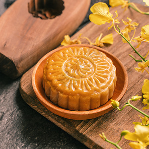 中秋节传统美食概念黑石板桌上的美丽月饼与茶糕模具花茶壶石板托盘兰花甜点桌子杯子食物蛋糕糕点背景图片