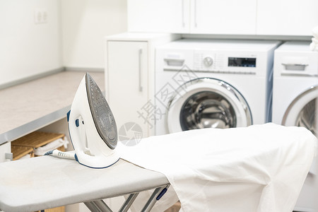 洗衣房用白衬衫和铁烫衣板杂物器具衬衫织物熨烫洗涤洗衣家庭作业工作发电机背景图片