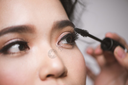 一位亚洲女性在眼睫毛上涂抹面膏刷子睫毛膏皮肤女士白色棕色女孩眼睛背景图片
