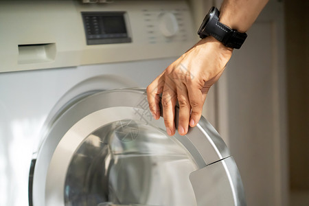洗衣服的手男人正在使用现代洗衣服浴室家务烘干机房间晴天衣服家庭民众男性洗衣机背景