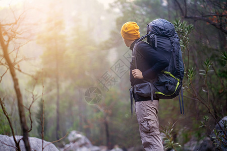 一个年轻旅行者背着背包 爬上山去背景图片