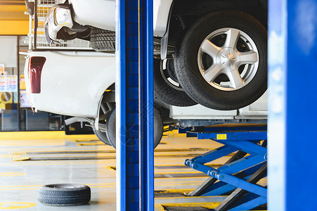 在汽车服务车库中心的汽车升降机上升起的皮卡车 用于更换轮胎 汽车维修和保养概念齿轮高清图片素材