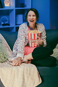 女孩在家里面对看喜剧电影 坐在沙发上看电视的千禧一代女性 娱乐的概念 积极的情绪背景图片