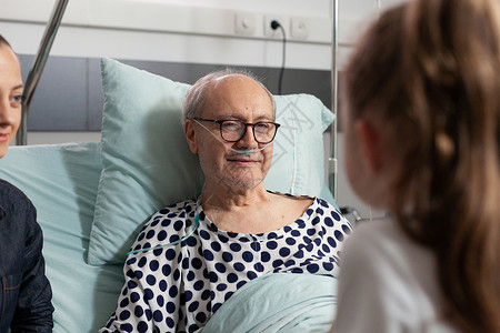 有选择地关注老年患病老人在床上与有照顾的外孙女交谈时背景图片