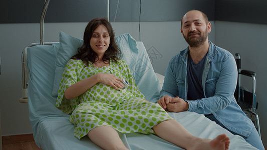 幸福的年轻家庭在医院病房预产期夫妻腹部母亲送货母性技术婴儿保健药品诊所坐着高清图片素材
