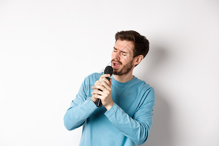 罗马男子在卡拉OK的麦克风里唱歌 站在白色背景上歌手商业成人发型办公室生活情绪成功广告男人背景图片