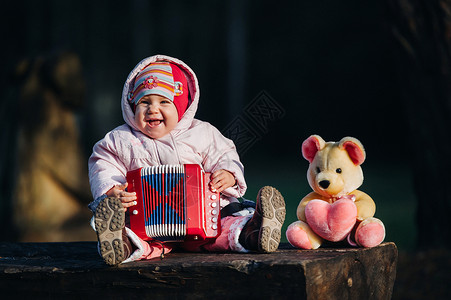 有趣可爱的女孩 一个穿着时髦牛仔裤的小孩拉手风琴 快乐宝贝玩游戏 可爱的萌娃 一个微笑的婴儿的美丽而富有表现力的笑声背景图片