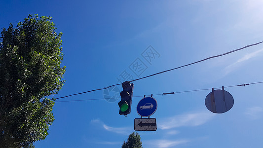 街上交通灯光和路牌紧贴着燃烧的绿灯树高清图片素材