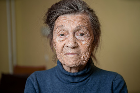 90 岁的可爱老妇人 头发花白 脸上有皱纹 穿着毛衣 肖像很大 微笑着 看起来很快乐 房间的背景 主题长肝抗衰 老人心情好奶奶老背景图片