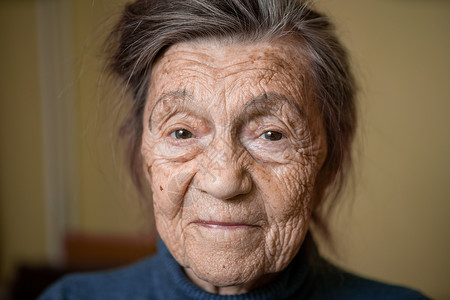 90 岁的可爱老妇人 头发花白 脸上有皱纹 穿着毛衣 肖像很大 微笑着 看起来很快乐 房间的背景 主题长肝抗衰 老人心情好病房老背景图片