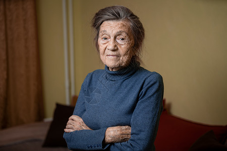 90 岁的可爱老妇人 头发花白 脸上有皱纹 穿着毛衣 肖像很大 微笑着 看起来很快乐 房间的背景 主题长肝抗衰 老人心情好退休祖背景图片
