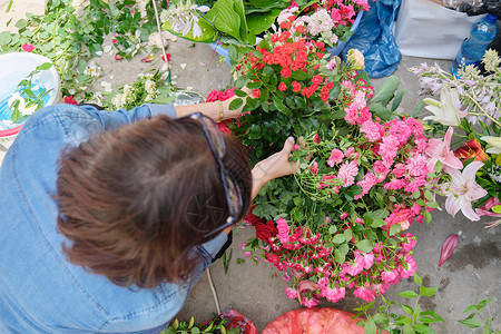 援助流程装饰花篮创建工作流程 在户外做花卉布局的女性花卉种植者婚礼组织店铺庆典篮子女士玫瑰花园花艺活动背景