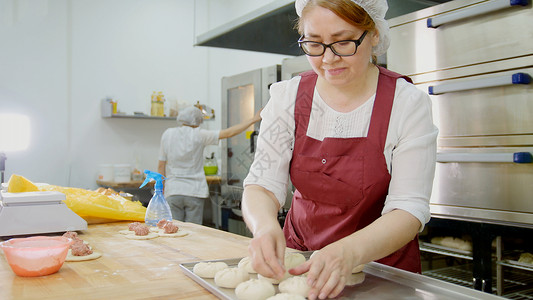女人戴眼镜和围裙 在面包店烤蛋糕炊具高清图片素材