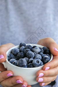 女人拿着装有冷冻蓝莓水果的碗 收获的概念 收集浆果的女性手 健康饮食理念 为冬天储备浆果 素食 vegan food女士营养花园背景
