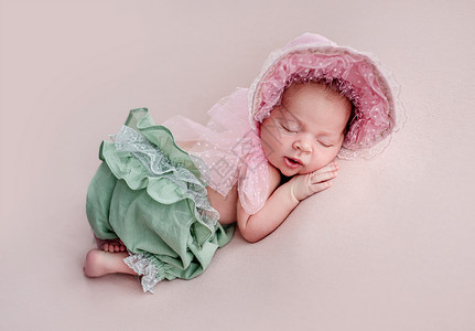 戴带带帽和长裤的新生儿压痛睡眠姿势说谎女孩幸福白色柔软度女士蕾丝背景图片