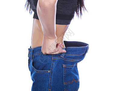 女人的特写展示了她的体重减轻 穿着白色背景中突显的旧牛仔裤裤子饮食损失成人身体腰部女孩减肥腹部女性背景图片