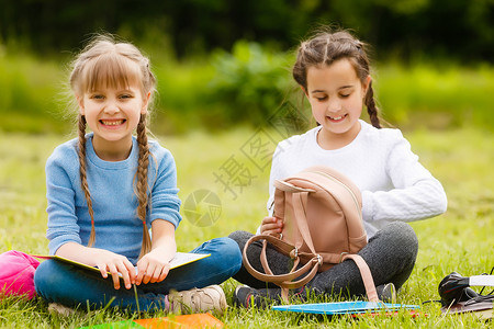 两个漂亮的女学生坐在公园户外的书房里 教女生或学生自然方面的课程 (笑声)背景图片