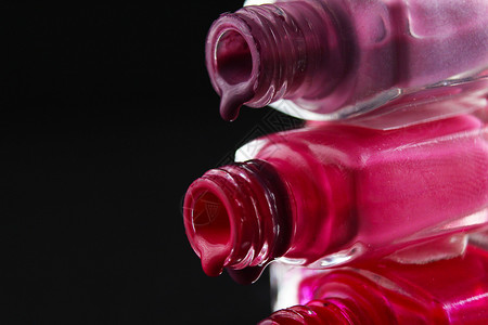 粉色瓶子美人背景保护者指甲油 从侧面的紫红色布贡迪粉色近视中从瓶子里喷出魅力紫色指甲配饰女性化妆品液体搪瓷抛光红色背景