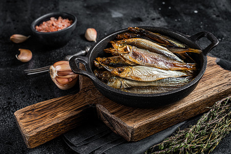 烧热的烟熏斑鱼和锅中鱼尾鱼 黑色背景 顶层视图背景图片