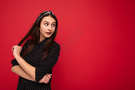 身着时髦的黑衣服 站立在红墙上 俯视面边边靠着红色墙边背景图片