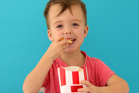 小男孩吃薯条室内小男孩在吃鱼和薯片时微笑男生童年孩子马铃薯土豆饮食小吃油炸享受营养背景