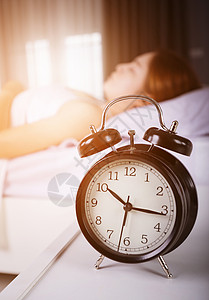 时钟显示上午10点 妇女清晨睡在有阳光的床上苏醒女性太阳说谎警报睡眠小时时间枕头房子日本人高清图片素材