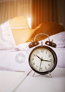 时钟显示上午10点 妇女清晨睡在有阳光的床上说谎女性枕头苏醒睡眠时间唤醒警报小时太阳醒来高清图片素材