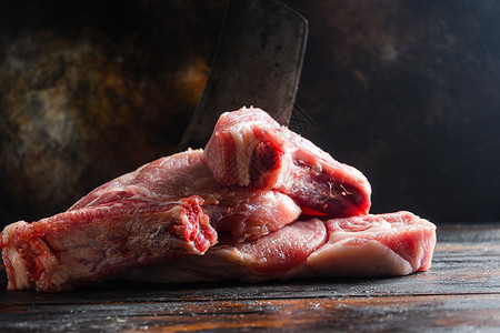 新鲜的猪排贝利农场 Raw猪肉在生锈背景上的木黑色木板条上涂黑 并砍切屠刀 侧视背景图片