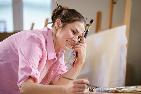 可爱的女人在艺术工作室的画布上作画 艺术家创作图片 艺术学校或工作室 使用颜料 画笔和画架 爱好和休闲的概念 工作区的女画家帆布快乐高清图片素材