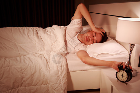 早上在卧室被闹钟惊醒时 不快乐的人醒来说谎休息时间警报男性唤醒苏醒睡眠失眠成人灯高清图片素材