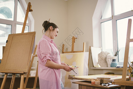 可爱的女人在艺术工作室的画布上作画 艺术家创作图片 艺术学校或工作室 使用颜料 画笔和画架 爱好和休闲的概念 工作区的女画家活动作坊高清图片素材