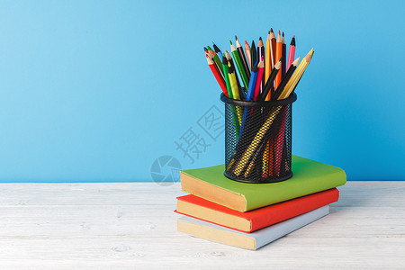 彩色铅笔杯和书本金属补给品笔筒桌子铅笔大学知识学校持有者图书背景图片