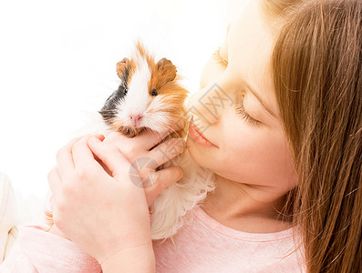 抱坚果仓鼠可爱的小女孩 在她的脸颊附近抱着小白鼠幸福哺乳动物金发女郎孩子友谊女孩朋友快乐宠物毛皮背景
