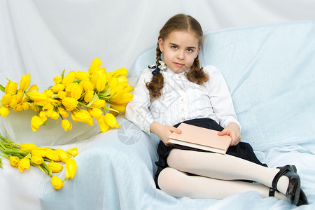 一位有黄色郁金香的勤奋女学生坐在T裙子粉色花束微笑母亲妈妈们花朵孩子工作室快乐夏天高清图片素材