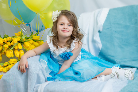 沙发上的小姑娘拿着一束鲜花童年裙子花朵微笑花束母亲快乐礼物孩子粉色天高清图片素材