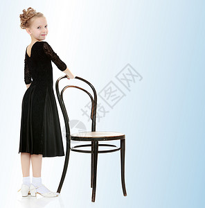 微弱的小舞者站在维也纳老椅子旁边工作室孩子天空头发婴儿蓝色童年背景图片