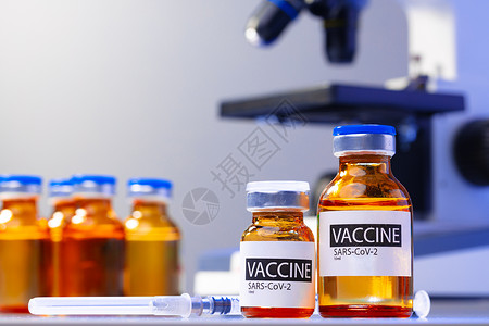 显微镜旁的Covid19疫苗Vial瓶子实验室治疗管子安瓶药剂药物背景图片