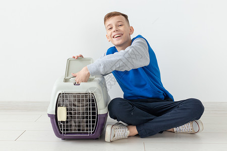 笑着的猫笑笑的男孩拿着一个笼子和一只苏格兰折叠猫坐在他旁边 坐在新公寓的地板上 保护宠物的概念工作室毛皮动物哺乳动物虎斑乐趣伴侣折叠婴儿背景