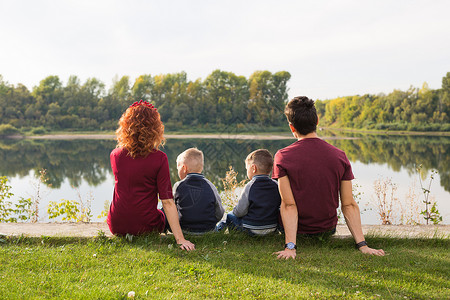童年和自然概念     家庭 小儿子坐在绿草上乐趣男人女性男性儿子们卷曲天空儿子头发成人季节高清图片素材