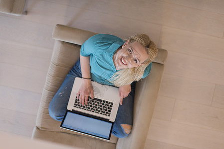 在家庭最高视野使用笔记本电脑的年轻妇女奢华会议屏幕房间生活沙发微笑幸福视频工作背景图片
