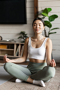 让你变得更美丽正念和冥想的概念 在家锻炼的亚洲年轻女性 在客厅的地垫上进行瑜伽冥想 变得专注技术成人重量运动装电脑女孩训练房间笔记本身体背景